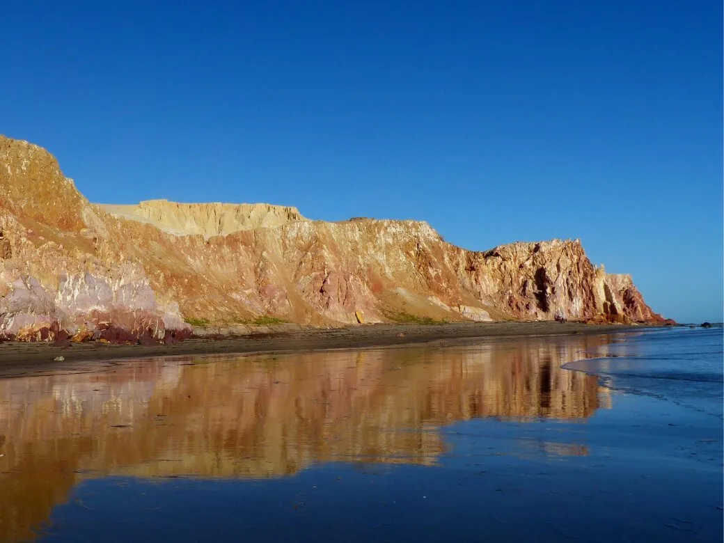 Reddish cliffs reflected at low tide
